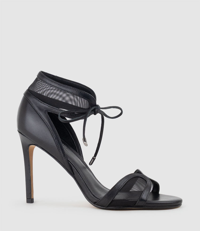 Black high-heeled sandal with mesh straps on a light gray background