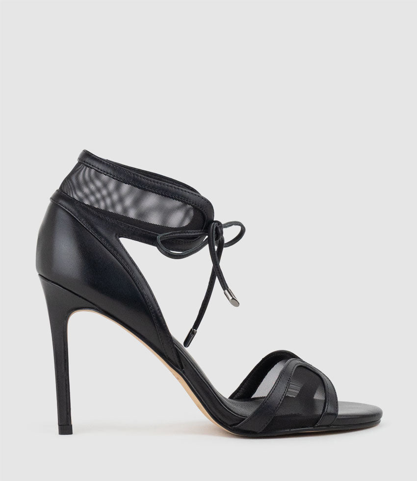Black high-heeled sandal with mesh details on a light gray background